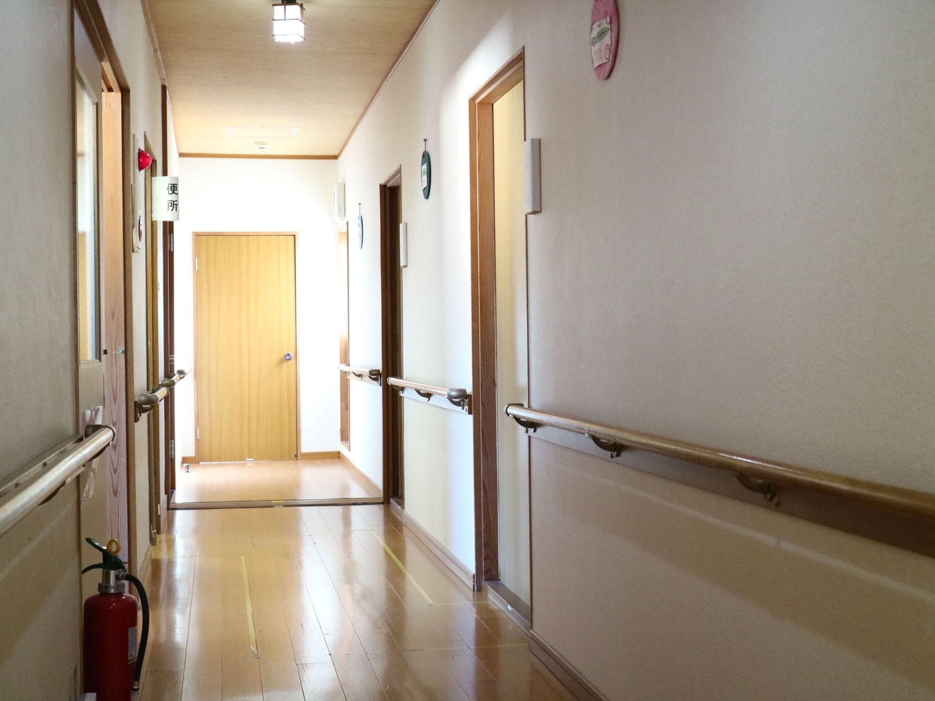 通路は、板張りの床、天井に白色の壁というデザインで、両脇に部屋が並んでおり、壁沿いには手すりが断続的に設置されている。