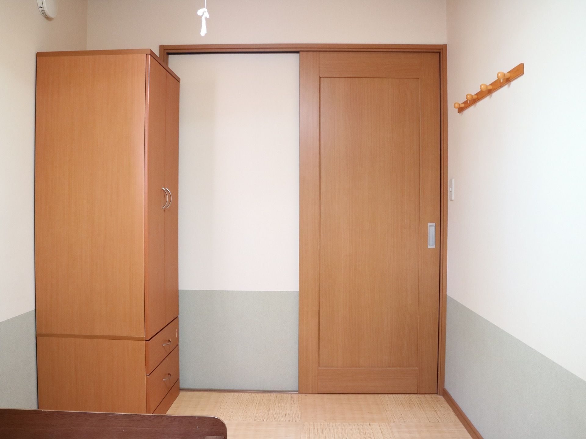 居室はコンパクトなワンルームで、壁は白色と緑色の２色、床は明るめの板張りである。ドアや収納タンスは光沢のある木製となっている。