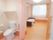 白を基調とした明るい居室である。トイレはカーテンで仕切られており、手すりや収納棚が取り付けられている。