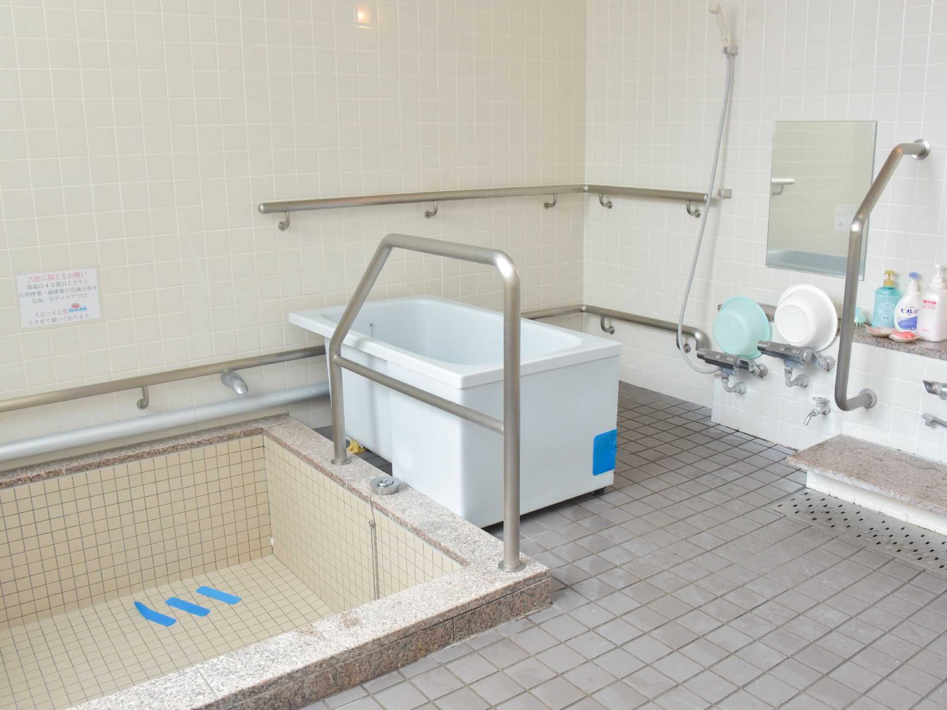 淡い水色が爽やかなデザインの小さめの浴槽も設置されている。全体的にグレー系の色でまとめられていて寛げる空間である。