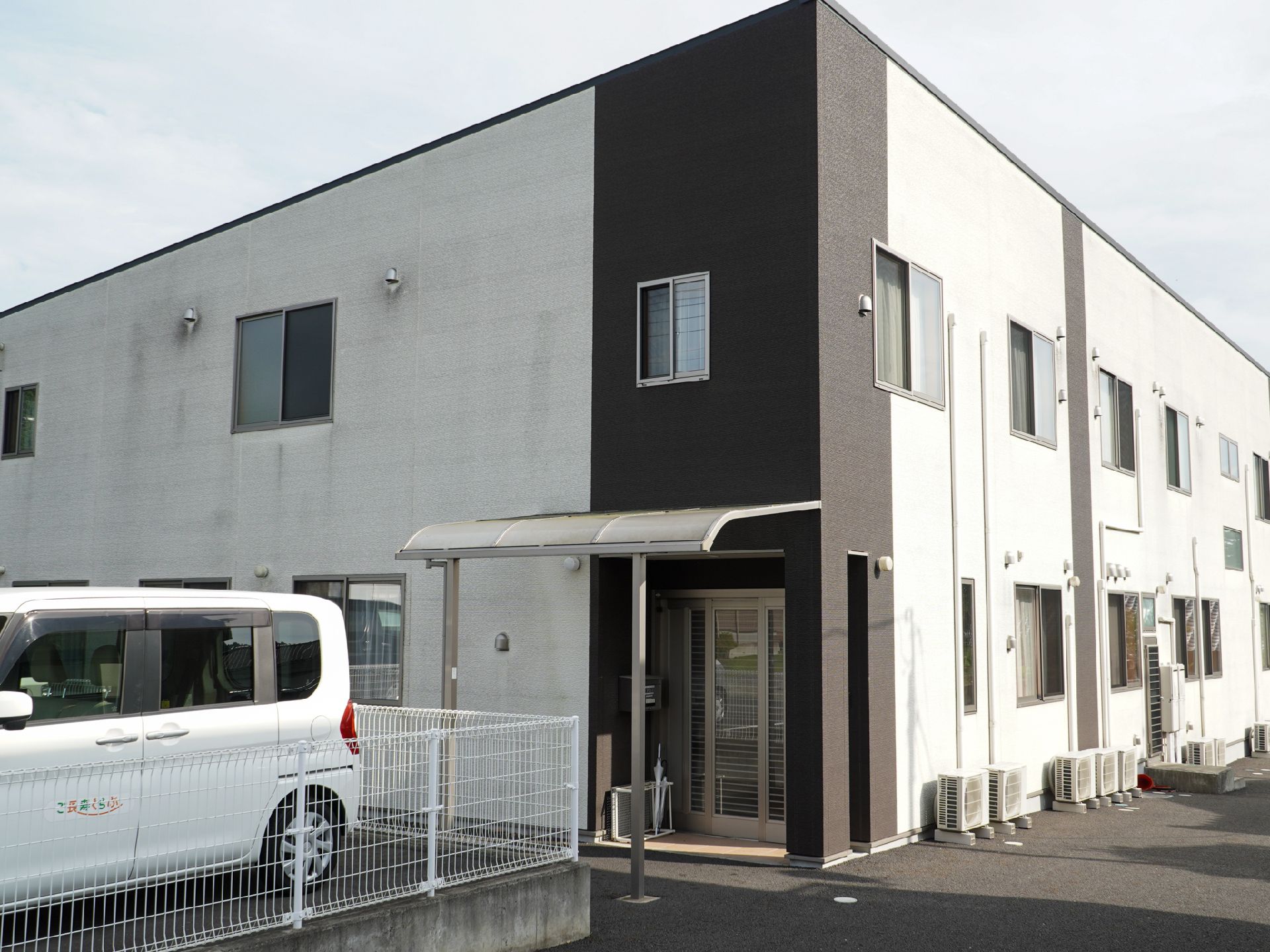 2階建てで白と黒の外観の建物