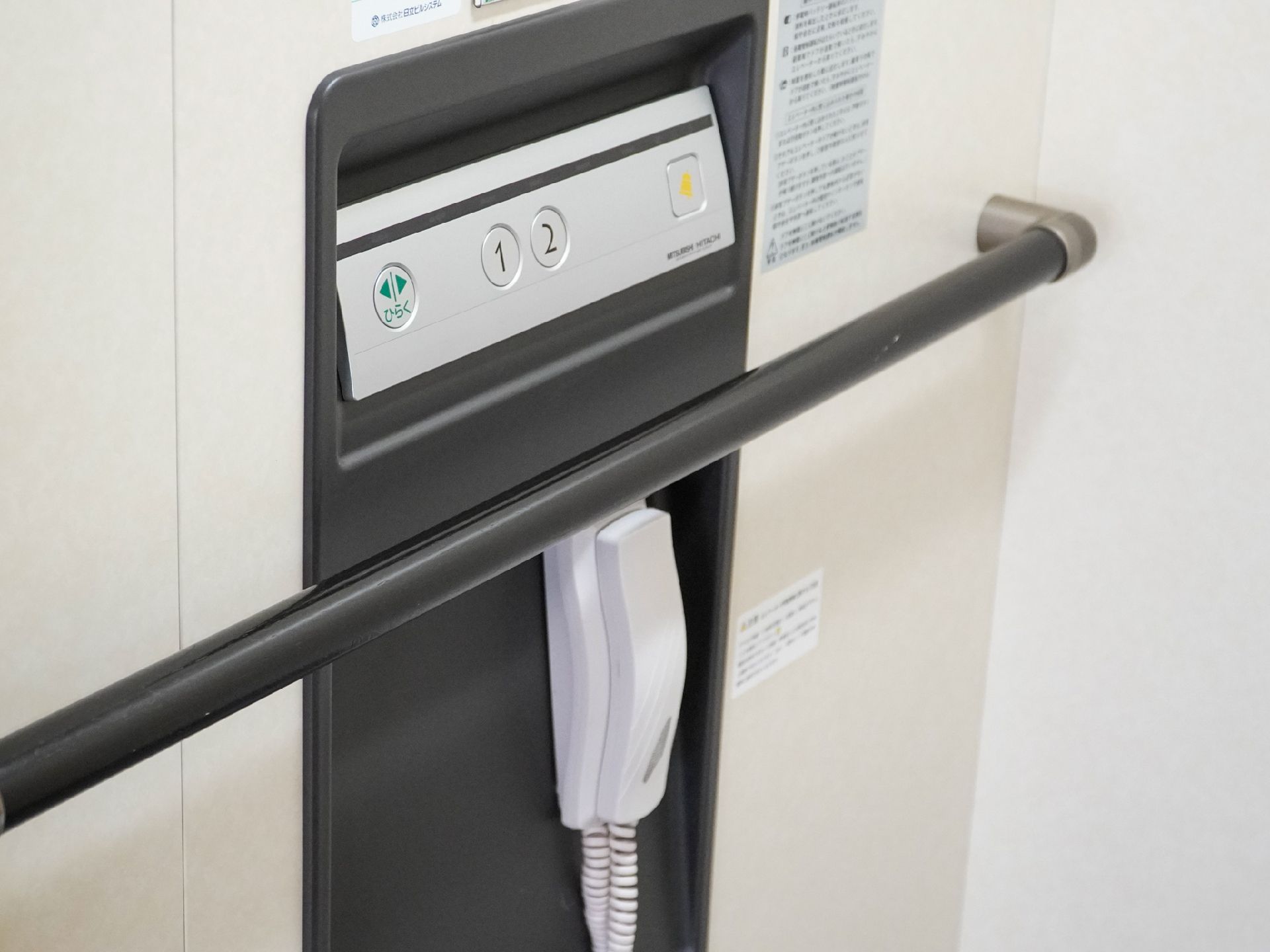 黒い手すりがついた白い壁に配置された受話器