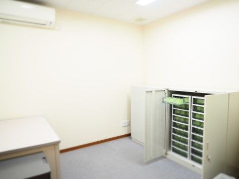 エアコンの設置された白い部屋。キャビネットとデスクが置かれている。キャビネット内の引き出しには入居者様の薬を保管している。