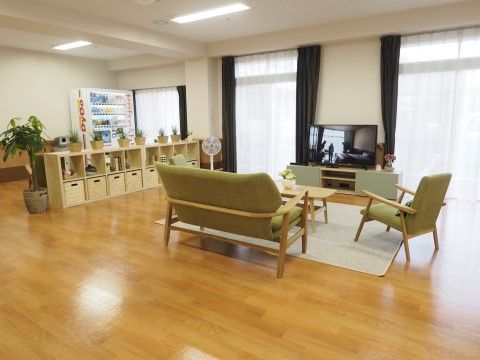 数人でテレビを見るように置かれたテーブルと大小のソファ。飲物の自動販売機も設置されている。扇風機、観葉植物がある。