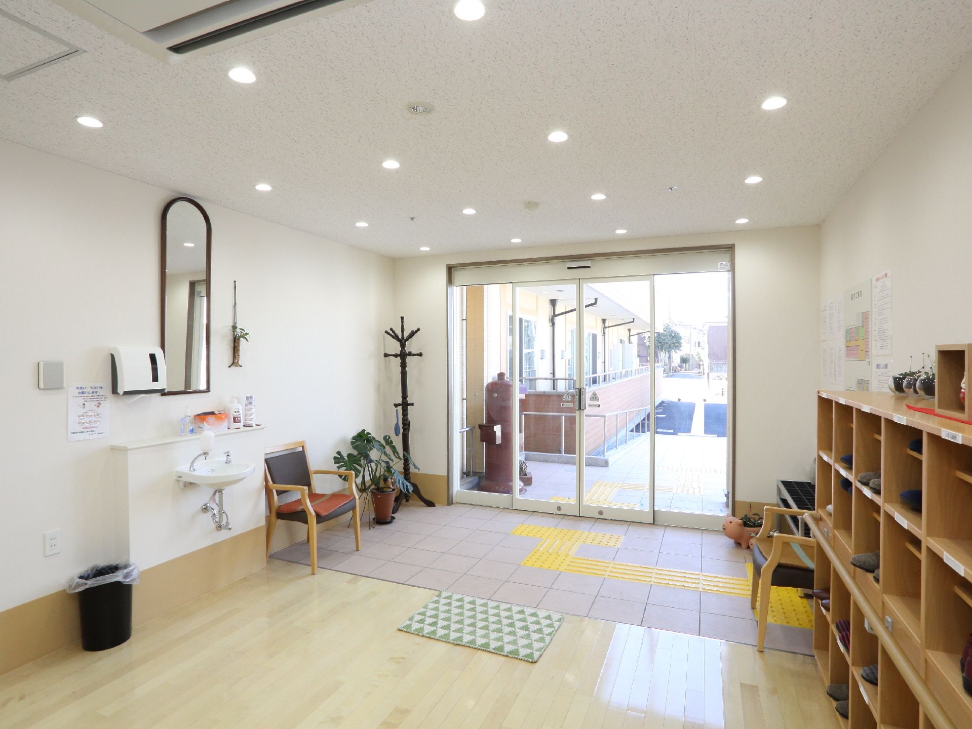 左の手洗い前には鏡が付いている。右側の靴箱の上には展示品が置かれている。玄関には観葉植物が置かれている。