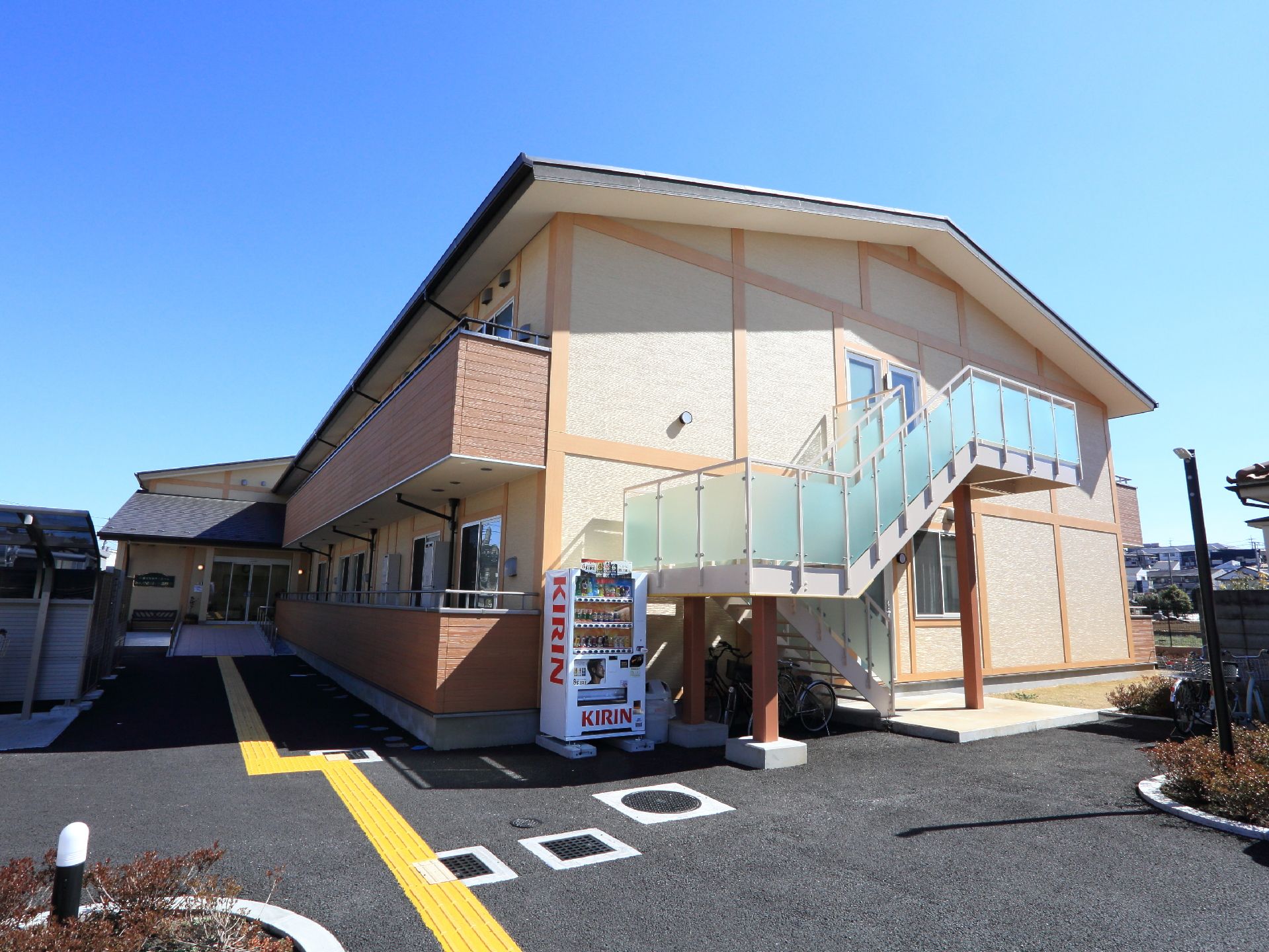 建物横には外階段が取り付けられている。横には駐輪場が設置されていて階段下にも自転車が置かれている。自動販売機も置いてある。