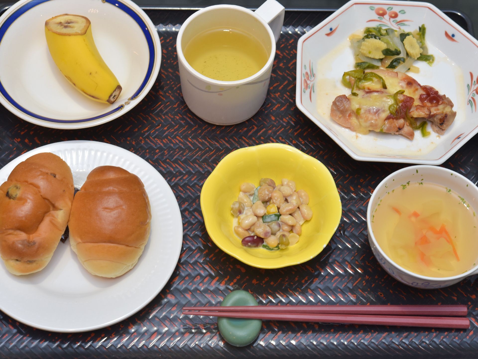 パン、バナナ、お茶、スープ、おかずが乗っているトレー