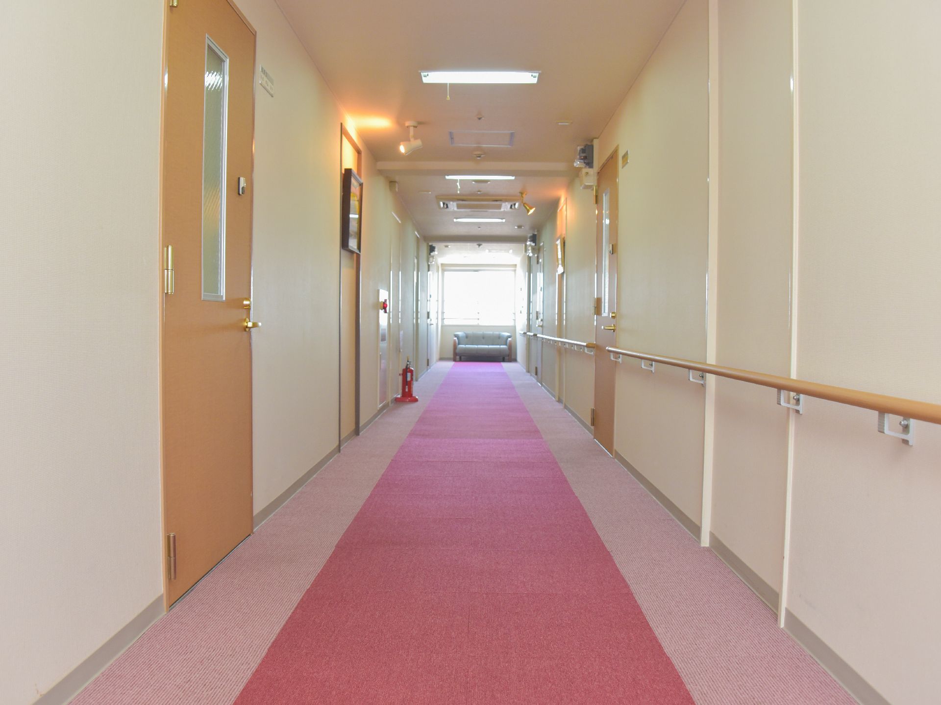 広く、赤を基調とした廊下は明るい印象。手すりが設置されているので歩行に不安がある人にも配慮されている