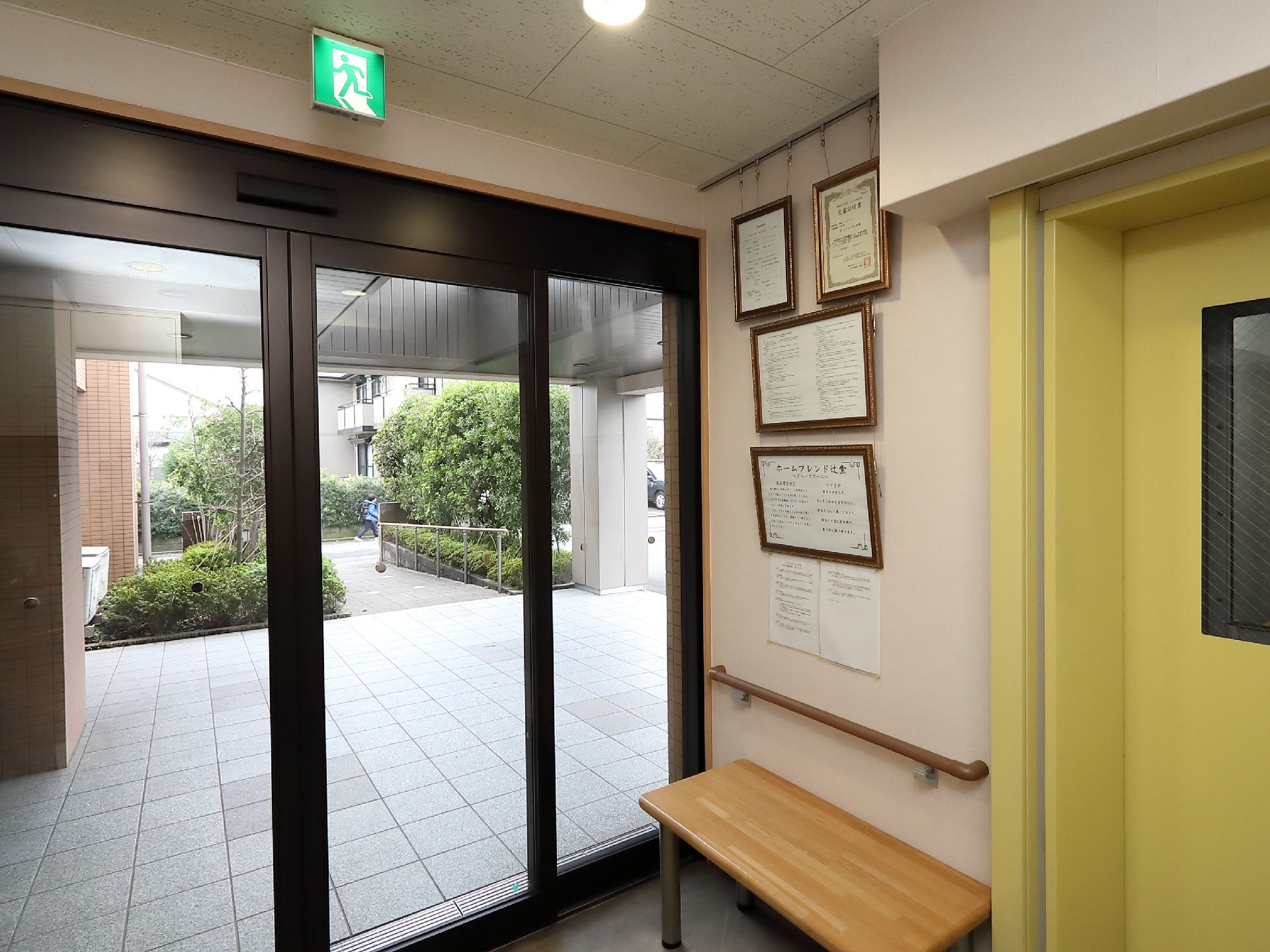 木のロングチェアと賞状が置かれている施設のエントランス