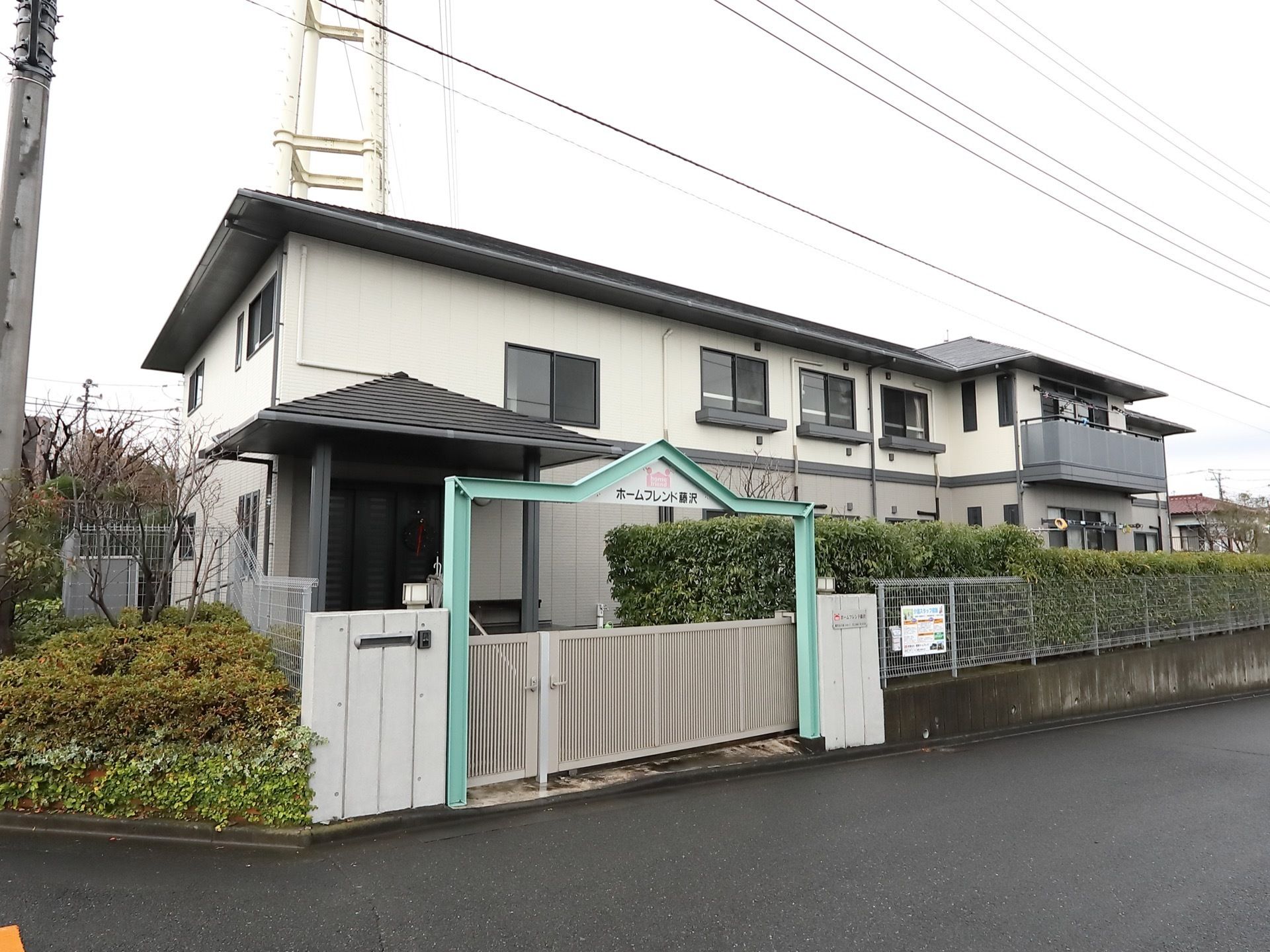 玄関の通路に入る前に、門が設置してある。門の上には、施設名を記したエメラルドグリーンの飾りがついている。