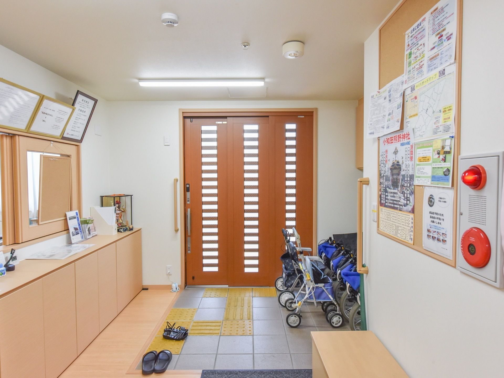 施設の玄関には、間口の広い玄関扉が設置されている。バリアーフリー続きで施設内へ進むことができ点状、線状ブロックが設置されている。