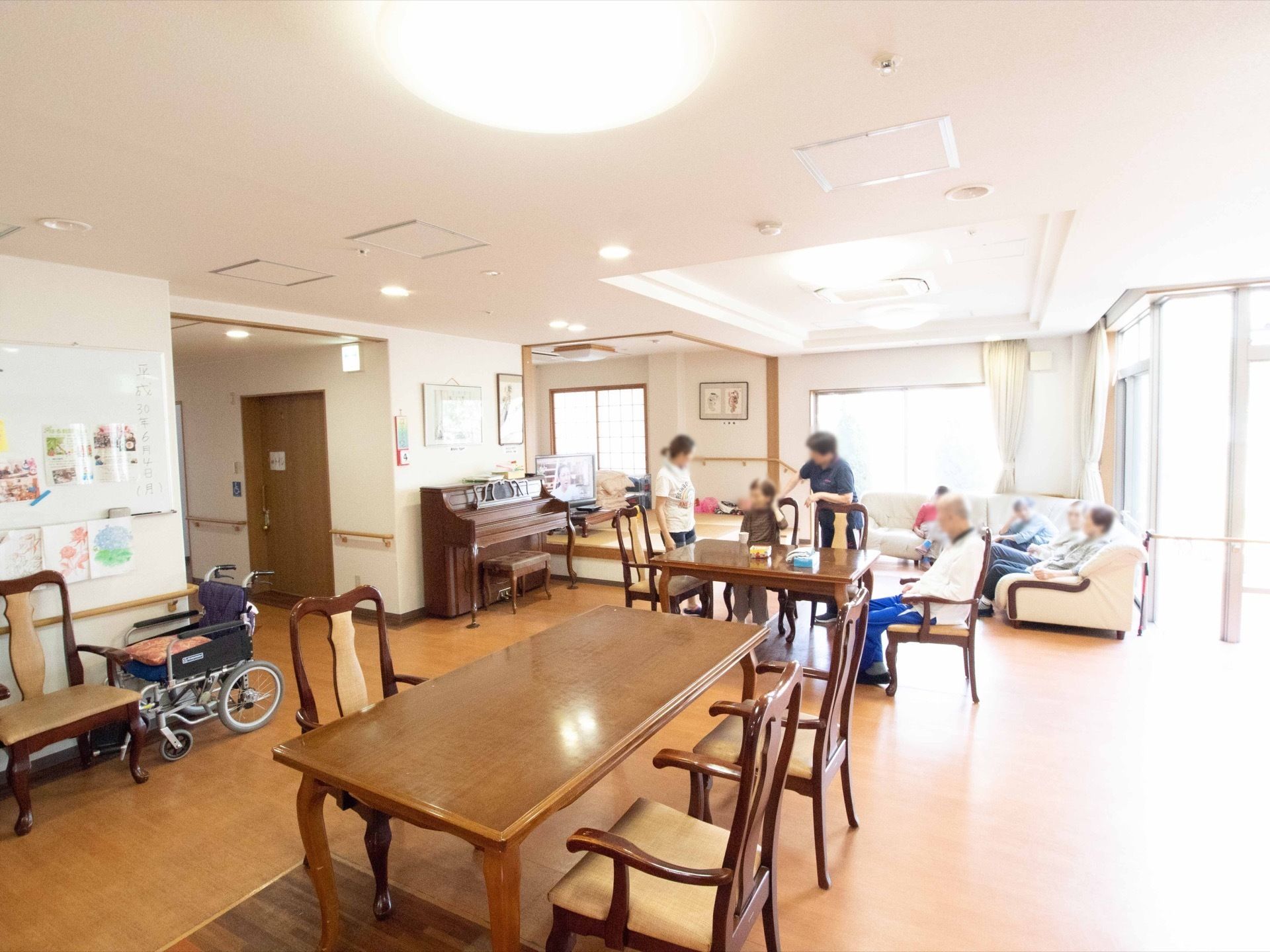 広々とした談話室。椅子とテーブル、L字型の大人数が座れるソファ、畳の敷かれた和室スペースがある。ピアノが置いてある。