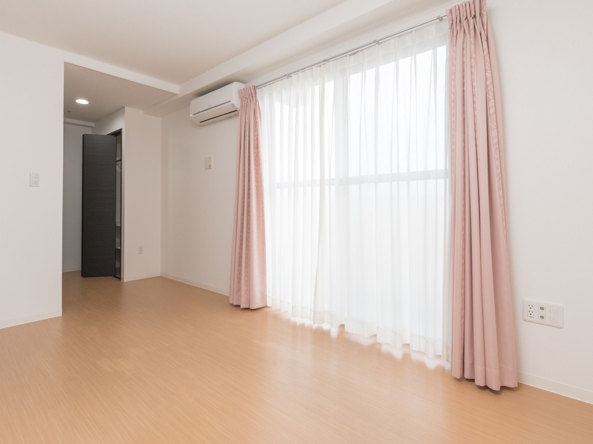 居室の床は、段差のないバリアフリーとなっている。壁にはエアコンがあり、サッシ窓にはカーテンが取り付けられている。