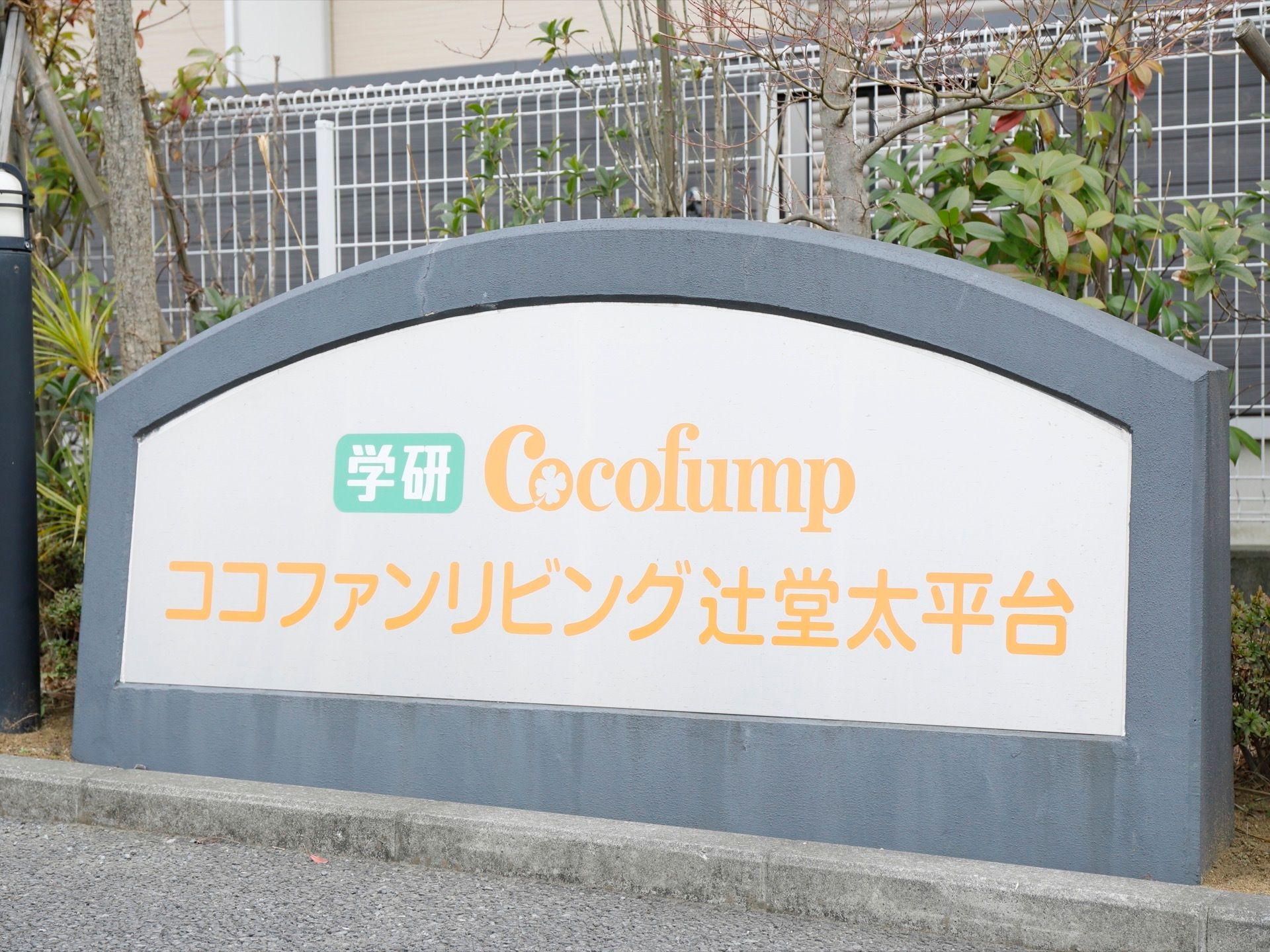 フェンスの前には植物が植えられ、かまぼこ型をした石造りの置物が置かれている。その中には、施設の名称が大きく表記されている。