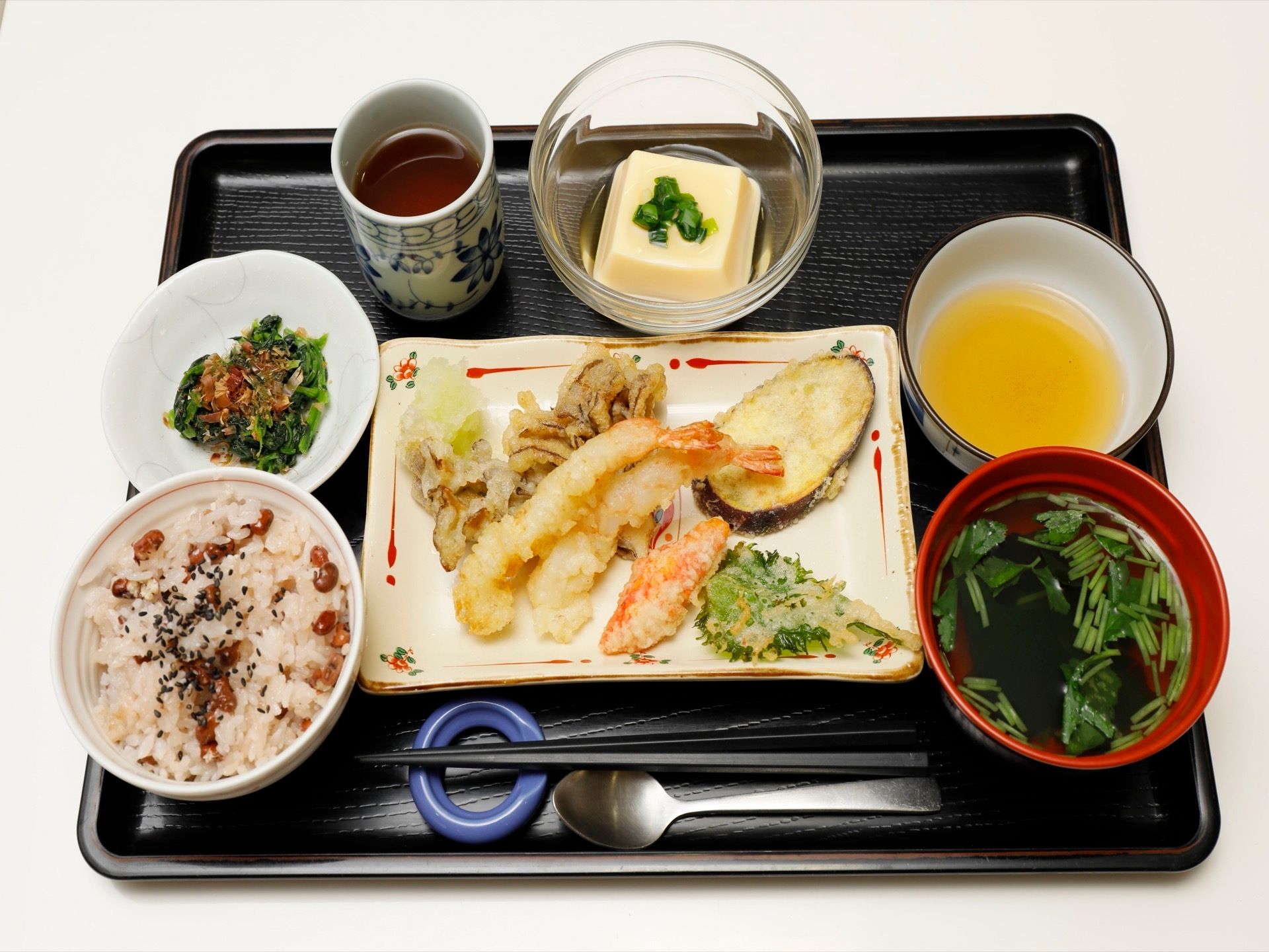 お盆一杯に載せられた食事でメインは天ぷらである。海老と茄子と大場、マイタケがのっている。お浸しやたまご豆腐などの小鉢もついている。