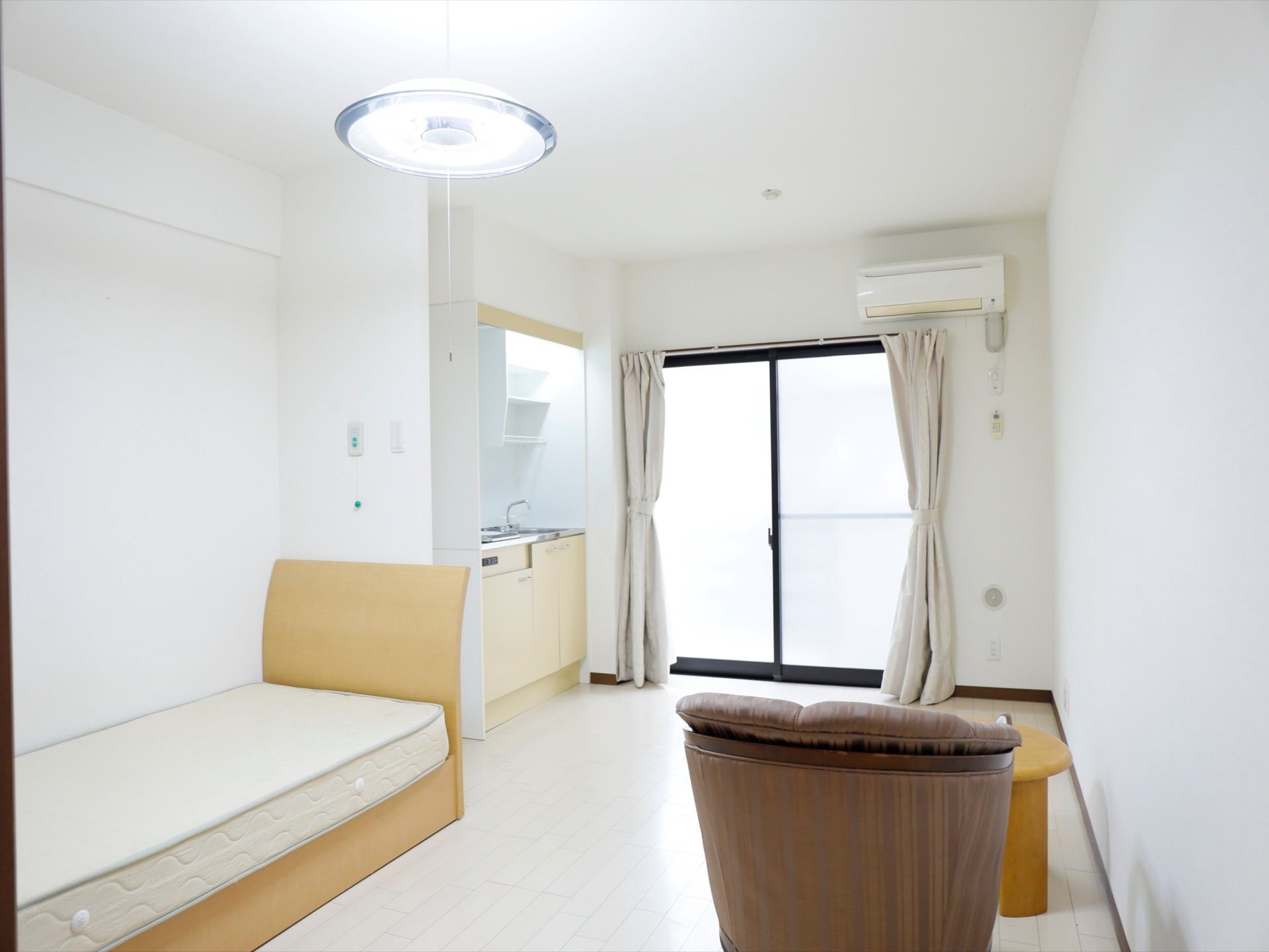 部屋には大きな窓があり、明るく広い室内になっている。窓際にはキッチンがある。ベッドにテーブル、１人掛けのソファーがある。