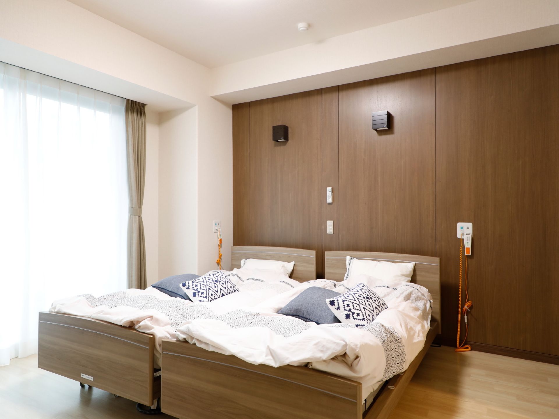 夫婦居室の寝室には、寝具付きの介護用電動ベッドが2台置かれており、壁には、ナースコールが設置されている。