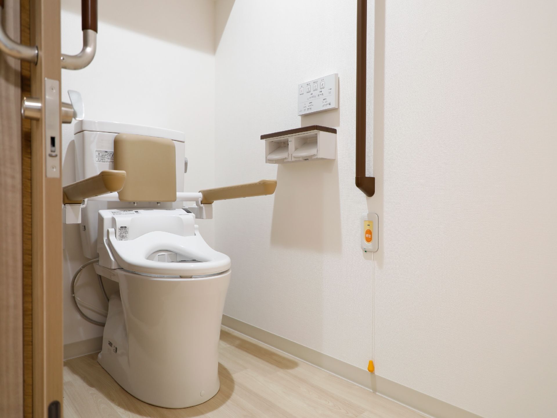 温水洗浄機能付きトイレである。壁や便器には手すりが設置されている。非常時の時に押す呼び出しボタンも備え付けらている。