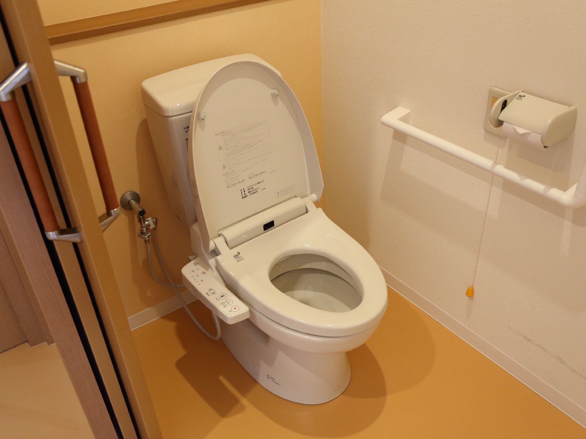 トイレの出入り口は引き戸式で、中には固定式の手すりも付いている。体調変化に対応できるナースコールがある