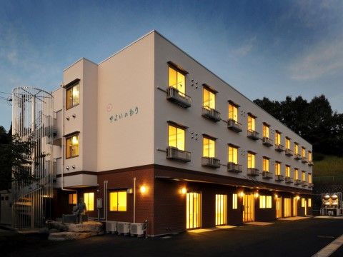 「有料老人ホームやよいのもり」の外観・夜。怖さを感じられない明るい空間。