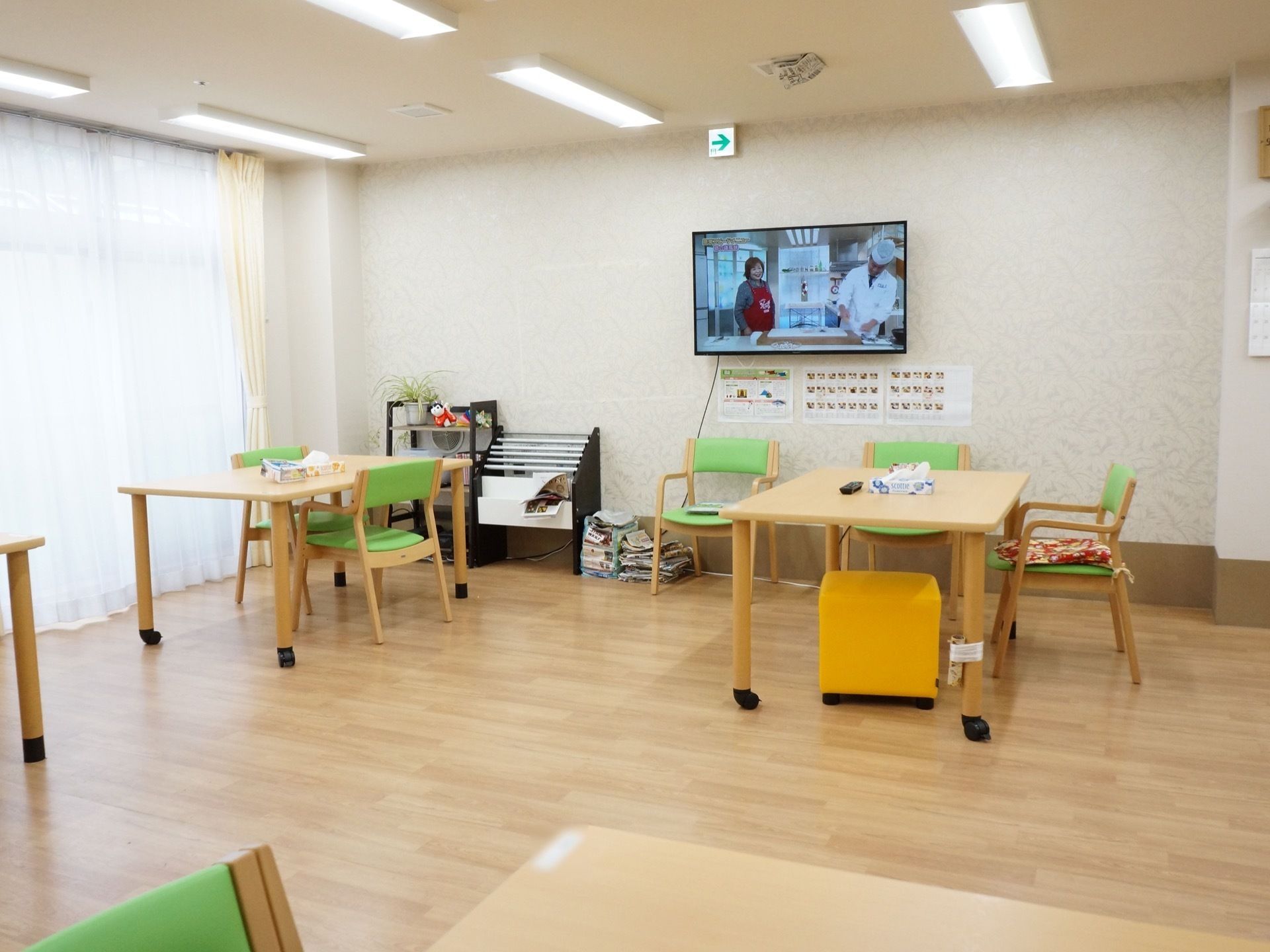 可動式のテーブルセットが置かれている。壁には大型の液晶テレビが取り付けられている。新聞ラックが用意されている。