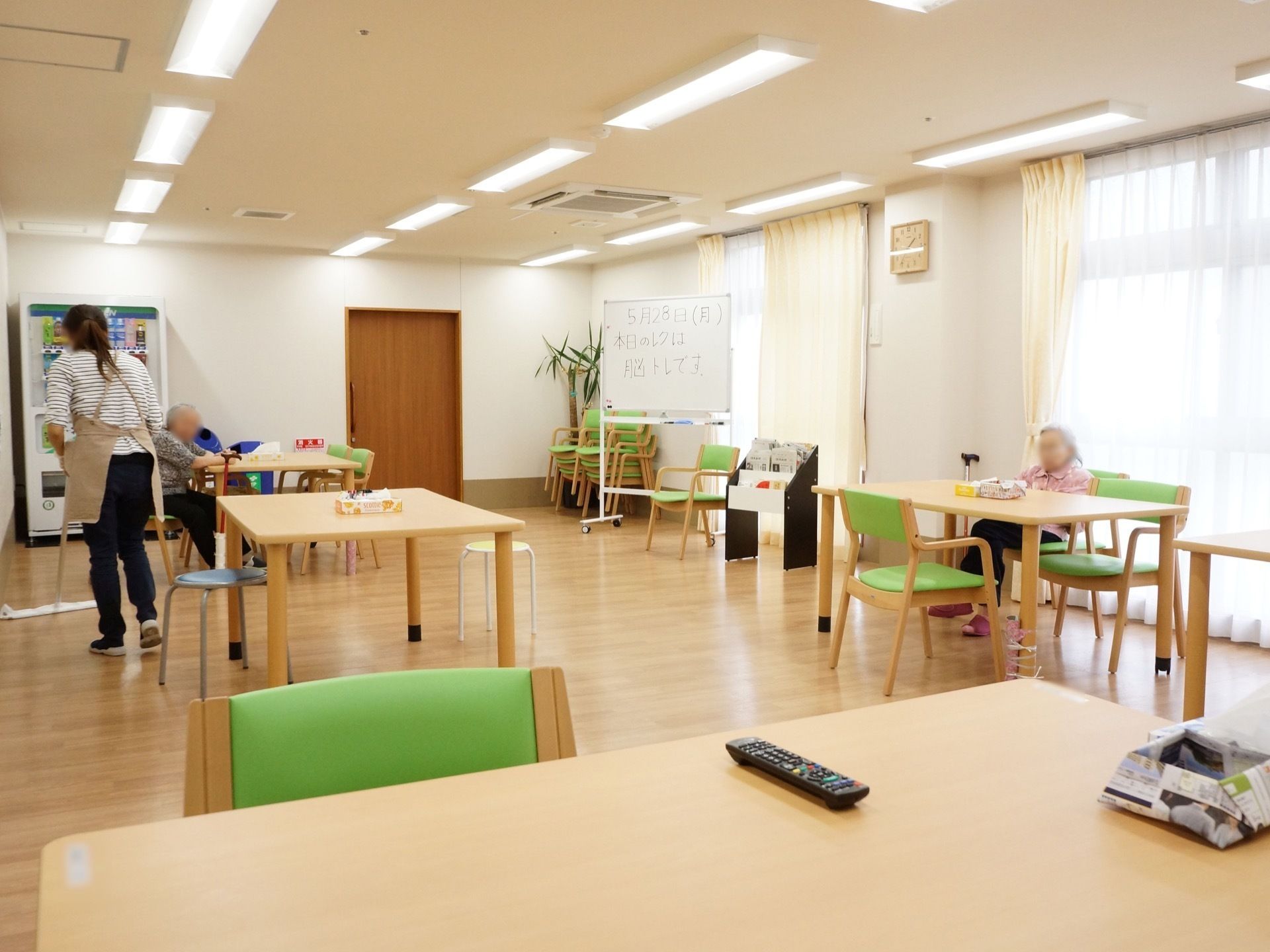一方の壁が全面窓になっている。薄いカーテンがひかれ、柔らかい外光が差し込んでいる。テーブルセットが並んでいる。