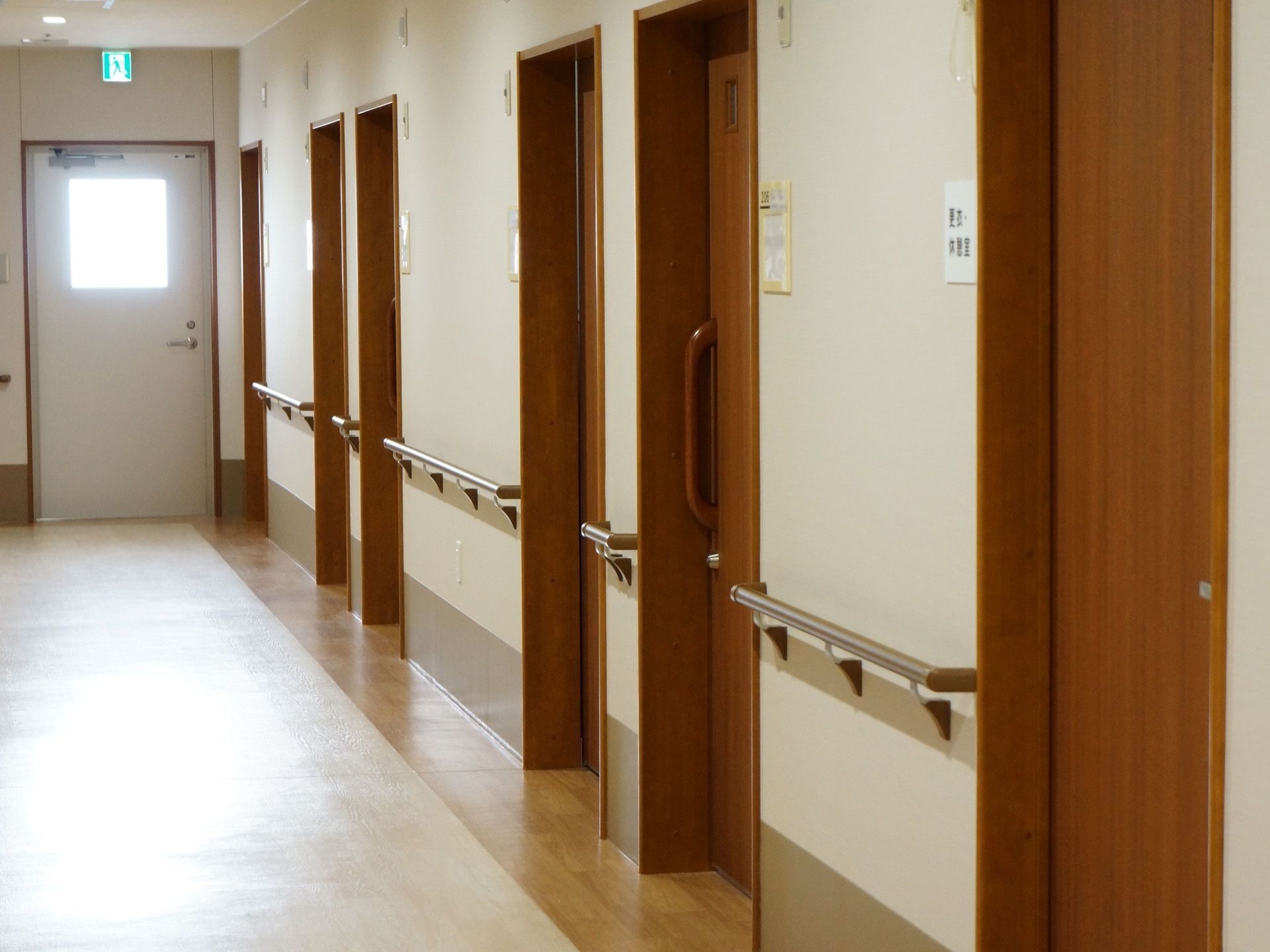 居室へのドアが並んでおり、ネームプレートが貼られている。壁に手すりが設置されている。突き当たりには非常口がある。