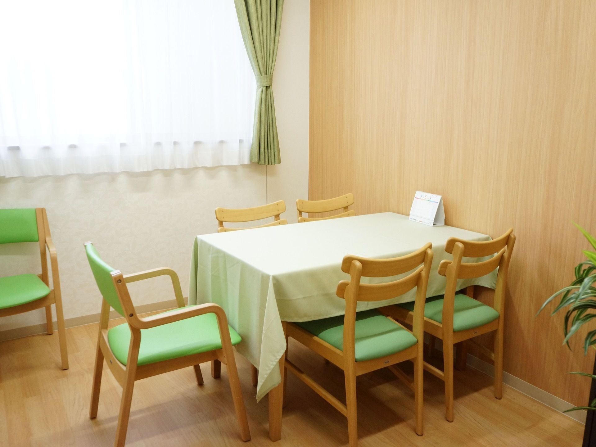 ご家族の方との面談などにご利用いただける談話スペースが用意されている。予備の椅子とカレンダーが置かれている。