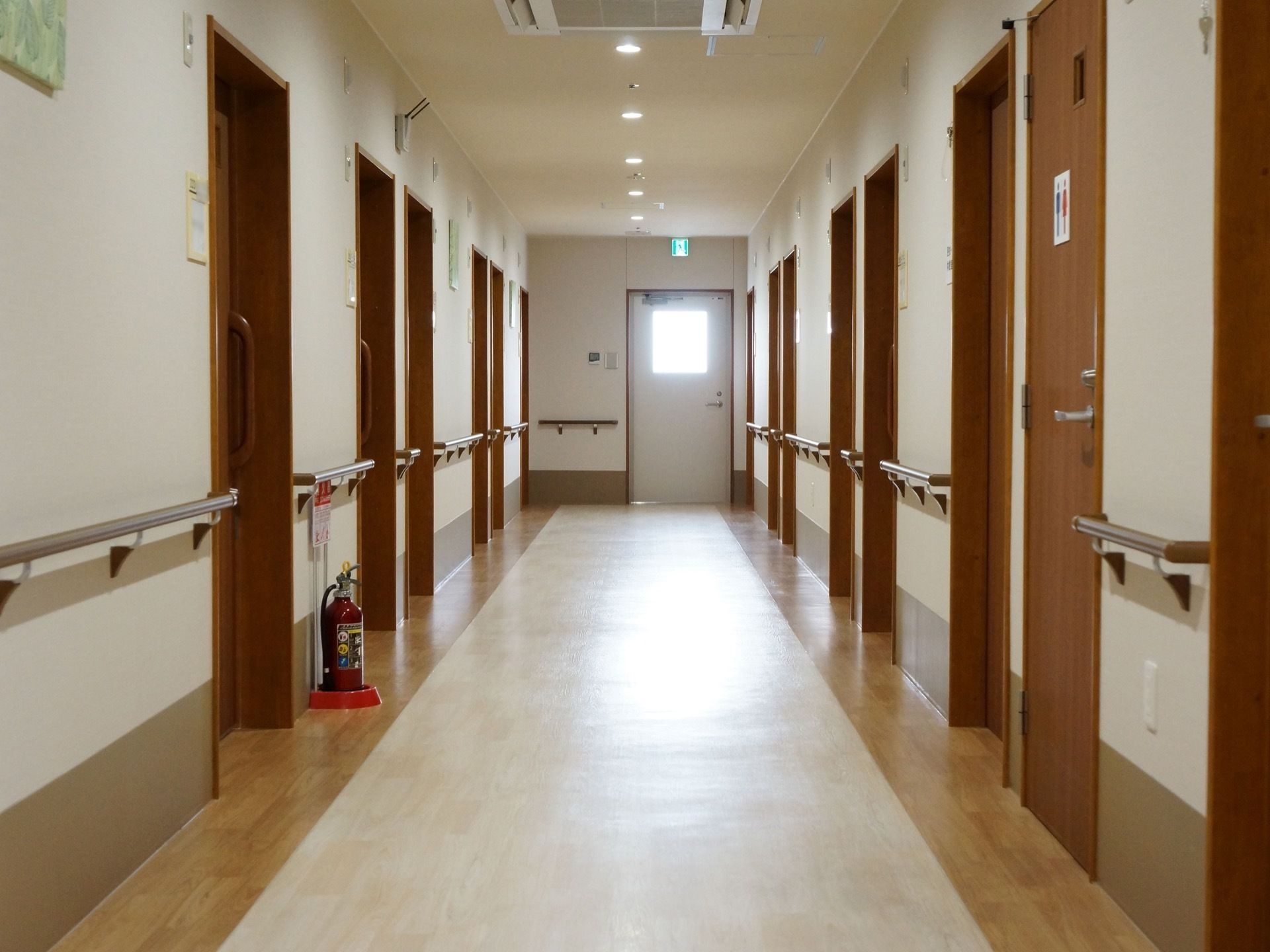 壁に手すりが設置され、消火器が置いてあるグループホームの廊下