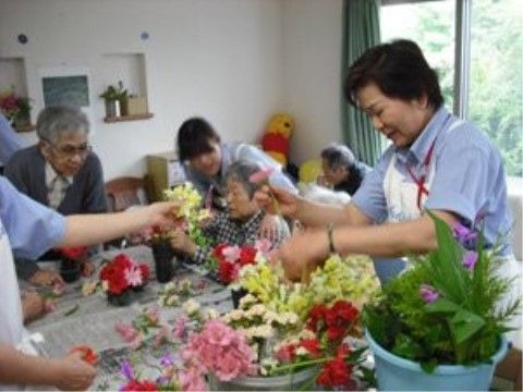 バケツに入ったたくさんの花と、入居者と施設のスタッフ