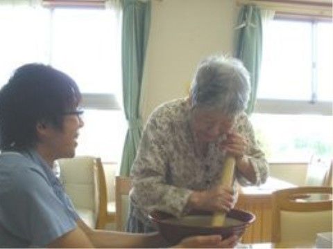 すり鉢を棒で擦っているお婆さんと、すり鉢を押さえている男性