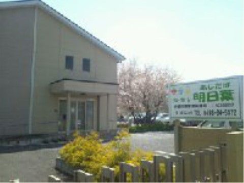 三角の屋根があり、小窓のついたホームの建物。スロープと階段を選んで、玄関まで進める。周囲には花壇に花があり、大きな木も植わっている。
