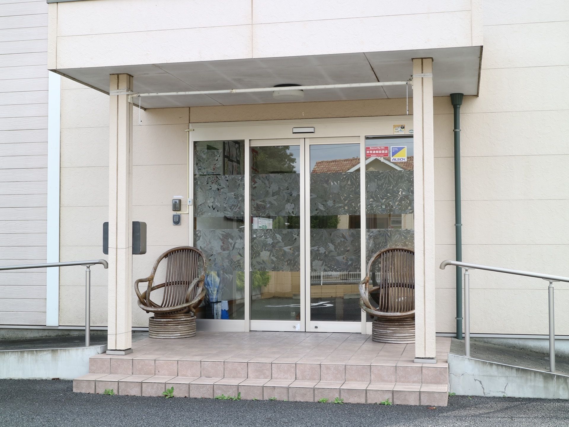 玄関はガラスの両開きの自動扉である。扉の両側に木製の椅子が置かれている。左右にゆるやかなスロープが伸びている。