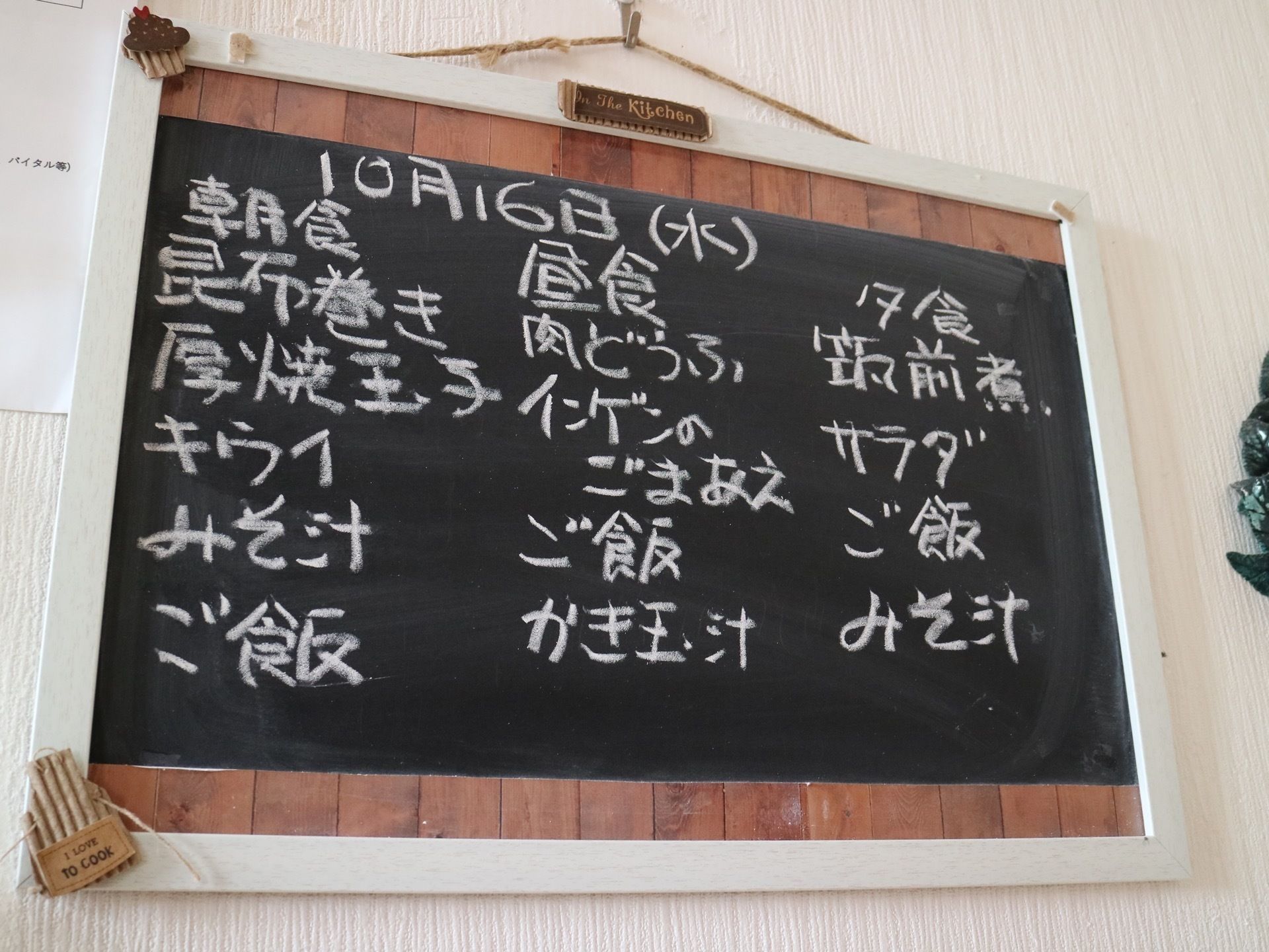 白い壁に木枠の付いた黒板シートが提げられている。朝食、昼食、夕食のメニューが白いチョークで書かれている。