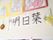 共有スペースの白い壁に、ホーム名が書かれた半紙や塗り絵がたくさん飾られている。折り紙の花もあり、明るい印象を受ける。
