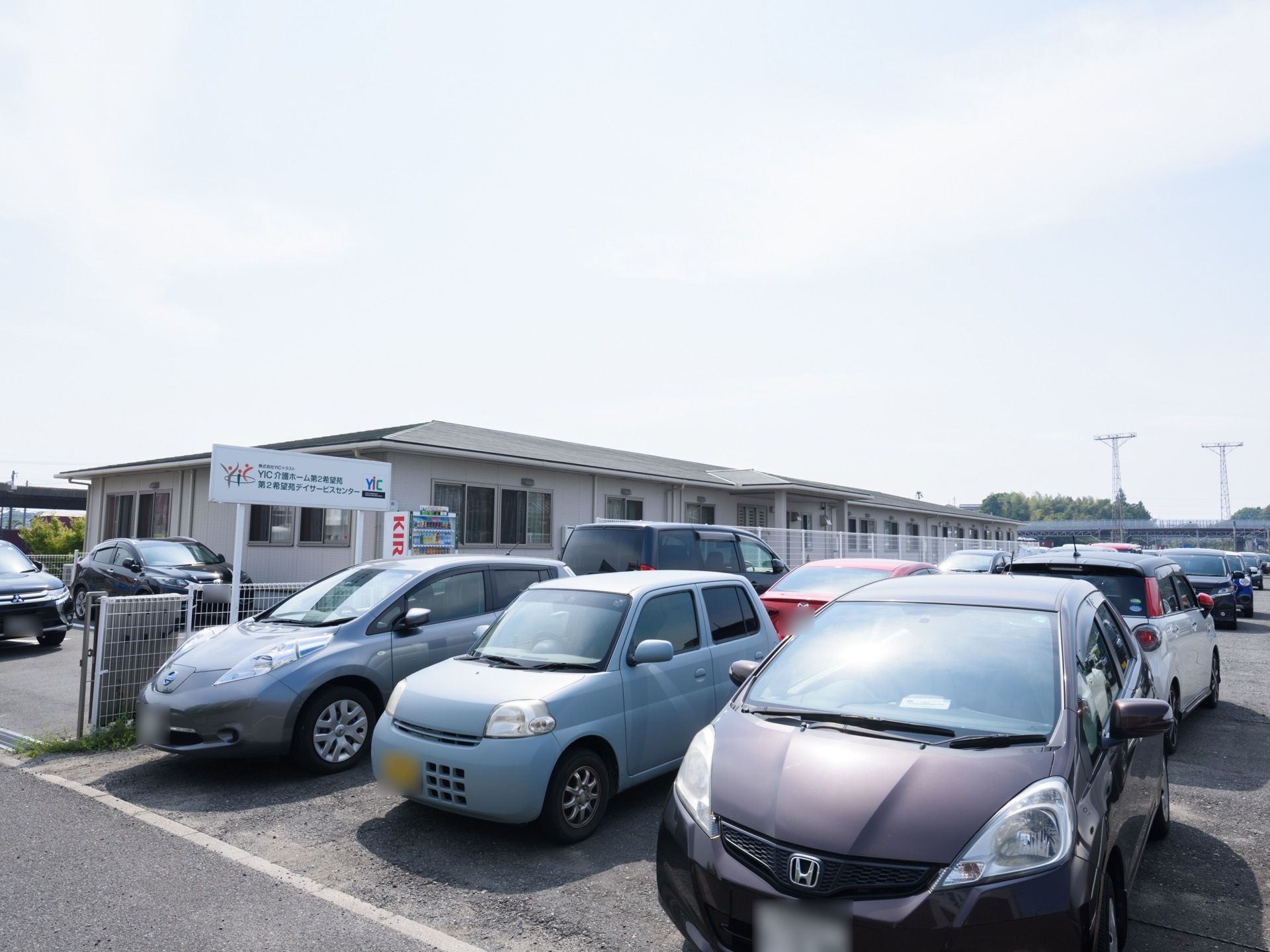 施設は平屋建てで、周囲には多くの駐車スペースがある。建物の外に飲み物の自動販売機が設置されている。玄関にはポーチがある。