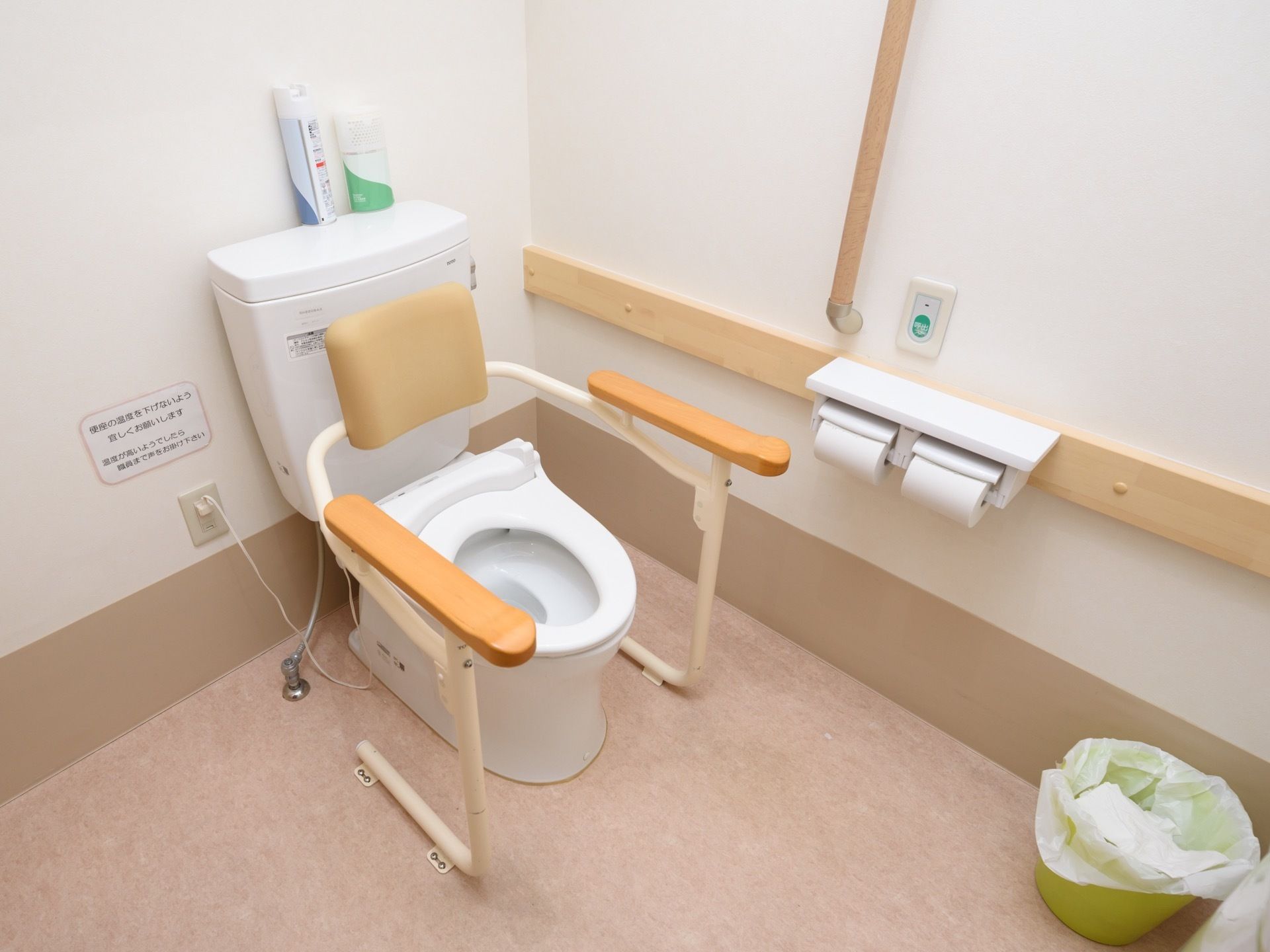 トイレは洋式である。便器の両側の手すりや背もたれがあることで、入居者様が安全にトイレを利用できる。便器の周囲にはスペースが広く取られている。