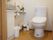 トイレには洋式便器が設置されている。2つのペーパーフォルダーの下にはゴミ箱が置かれている。手洗い場もある。