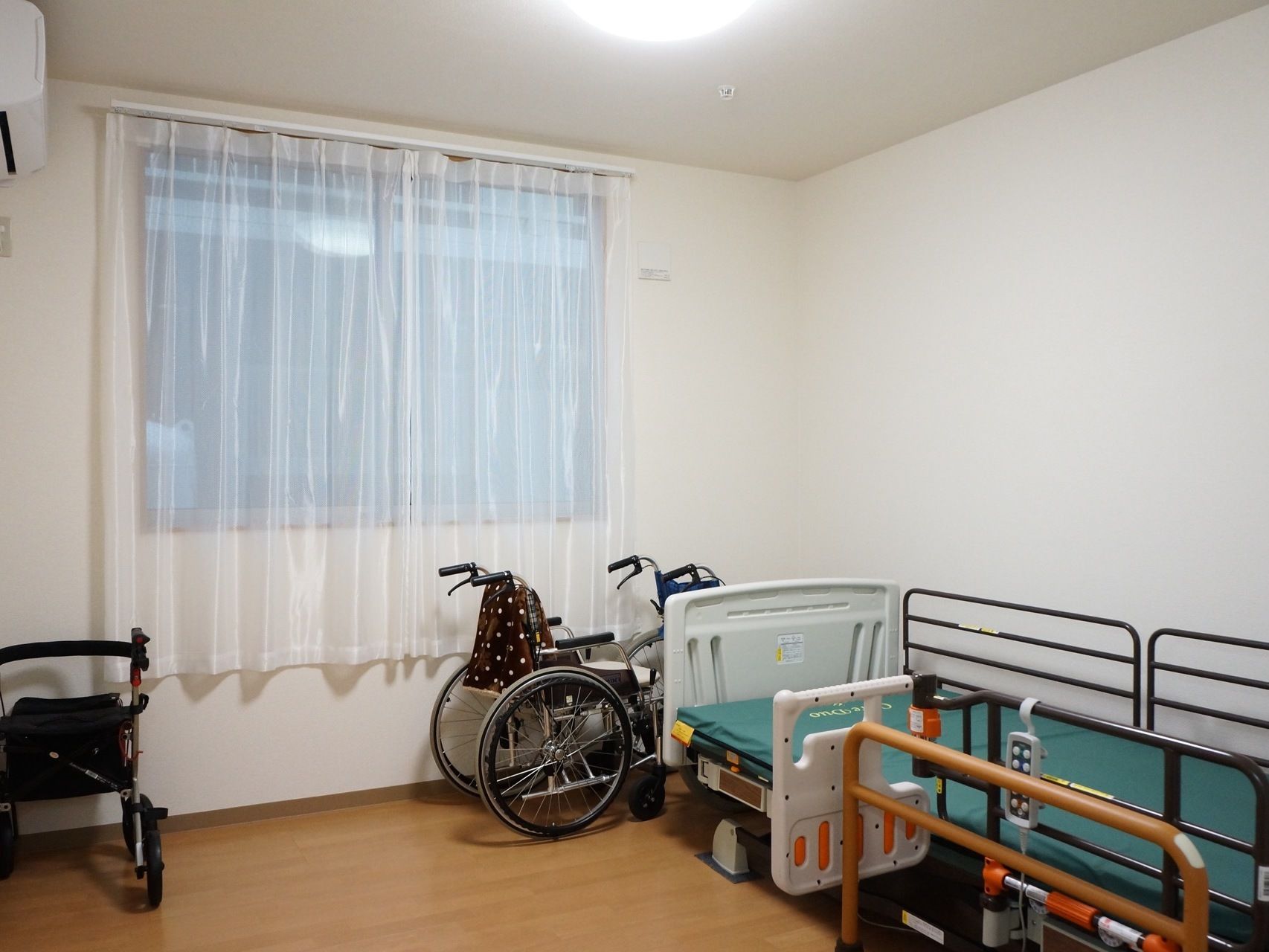 大きな窓がある居室には電動式ベッドが置かれており車椅子の方が乗り降りしやすいような手すりが設置されている。
