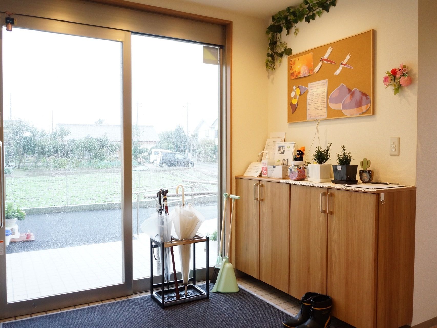 広く開閉するガラス扉が設置されている玄関の壁や靴箱の上には植木鉢や人形が飾られ明るい雰囲気になっている。
