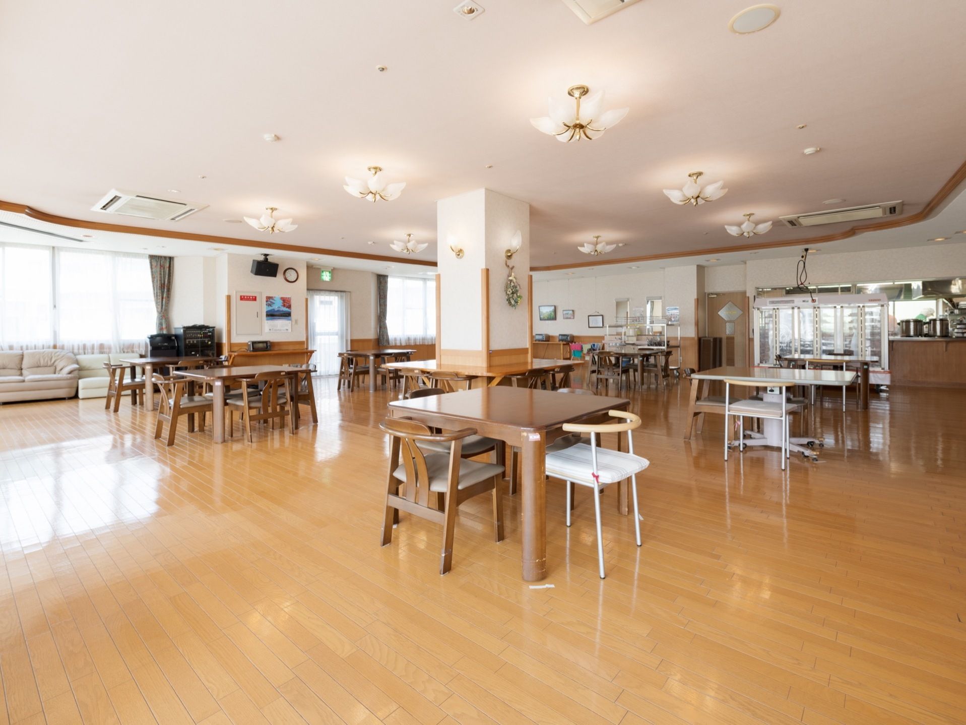 広く開放的な食堂に、テーブルと椅子が複数配置されている。天井には、上品なデザインの照明が備えつけられている。