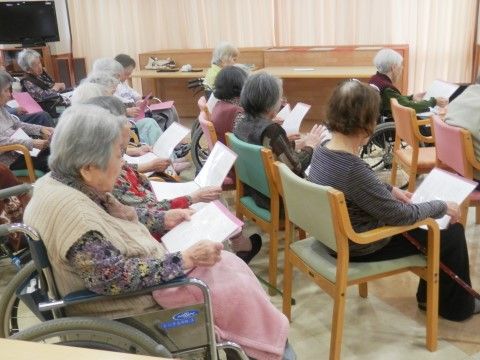 座って紙に書かれた文字を読んでいるグループホームの入居者