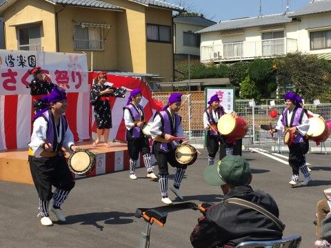 紫色の頭巾をかぶって小さな太鼓を叩いている人と踊り子