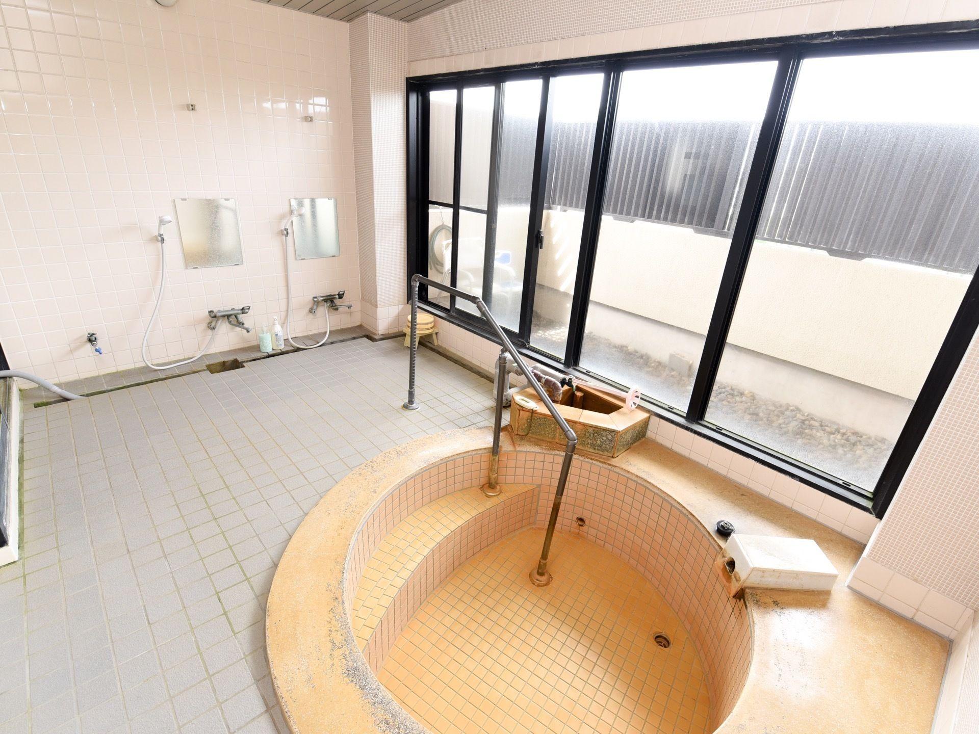 シャワー台と、手すりと階段がついた円形の浴槽が設置してある。大きめの窓の外には高めの柵が設けられており、プライバシーも守られている。