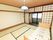 畳の部屋に電動ベッドが置かれている。障子の向こうにはトイレが設置されており、カーテンが付けられている。