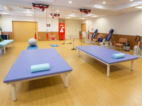 青いベッドやトレーニング機器が置かれているトレーニングルーム