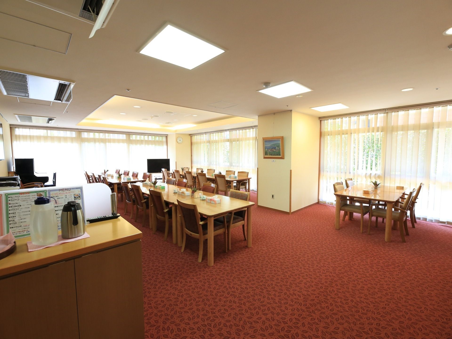 食堂は全面に大きく窓が設けられていて、白いレースのカーテンが掛けられている。床には赤いカーペットが敷かれている。