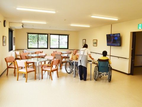 車椅子の利用者と女性のスタッフがいる、施設の共有スペース