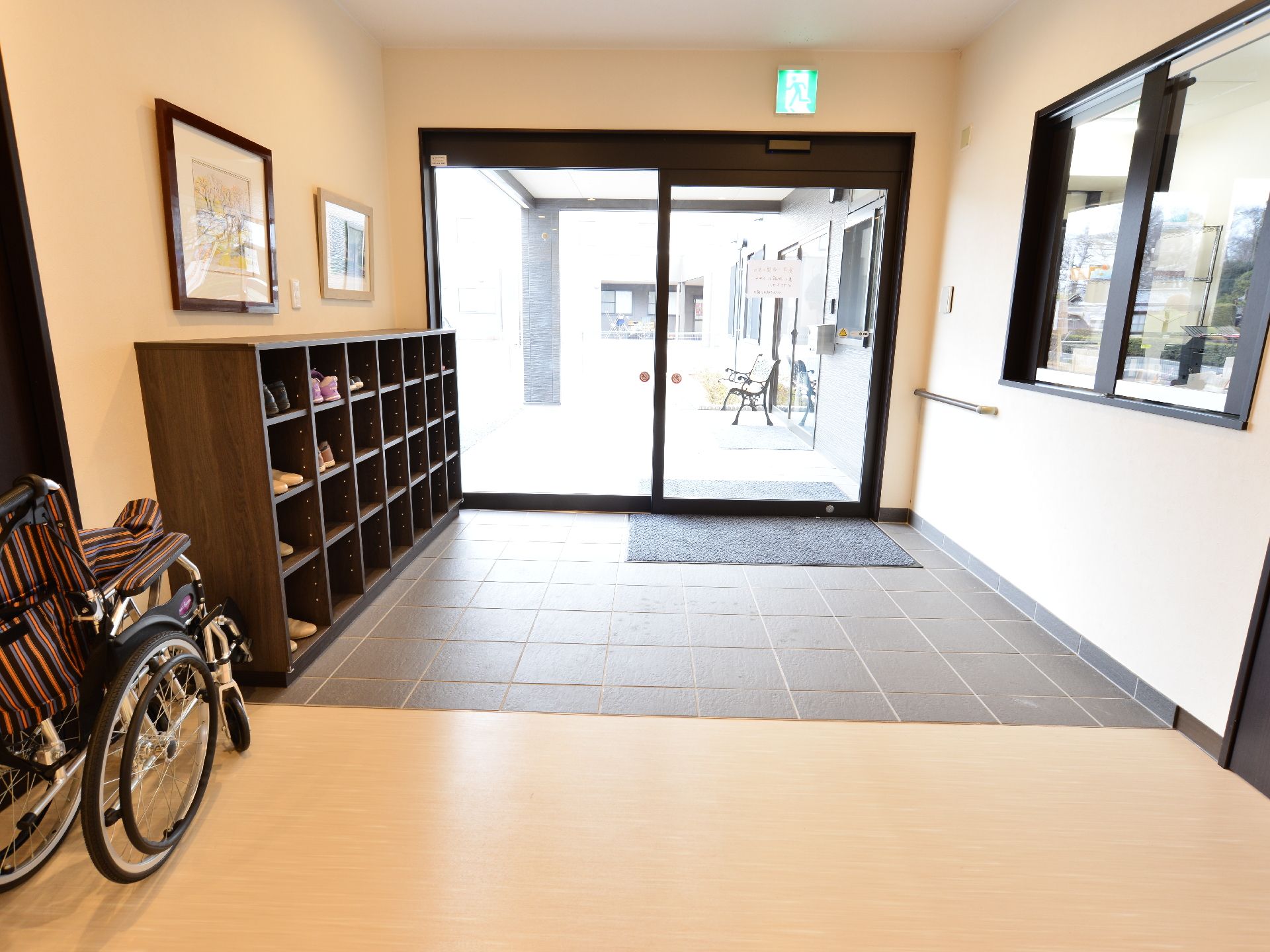 ガラス扉から自然光がたっぷり入る明るいエントランス。車いすでも利用しやすい段差のないバリアフリーで下駄箱や受付もある。