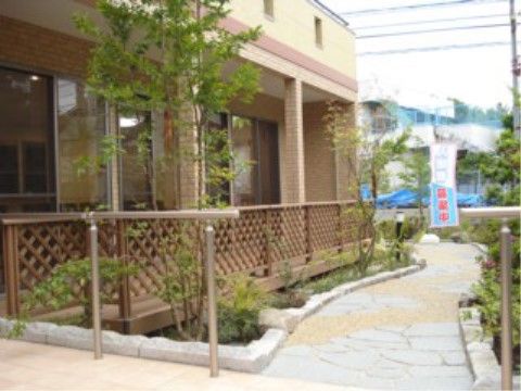 茶色の柵で仕切られている、グループホームの外にある道